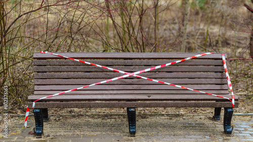 A park bench cordoned off with red and white striped barrier tape photo