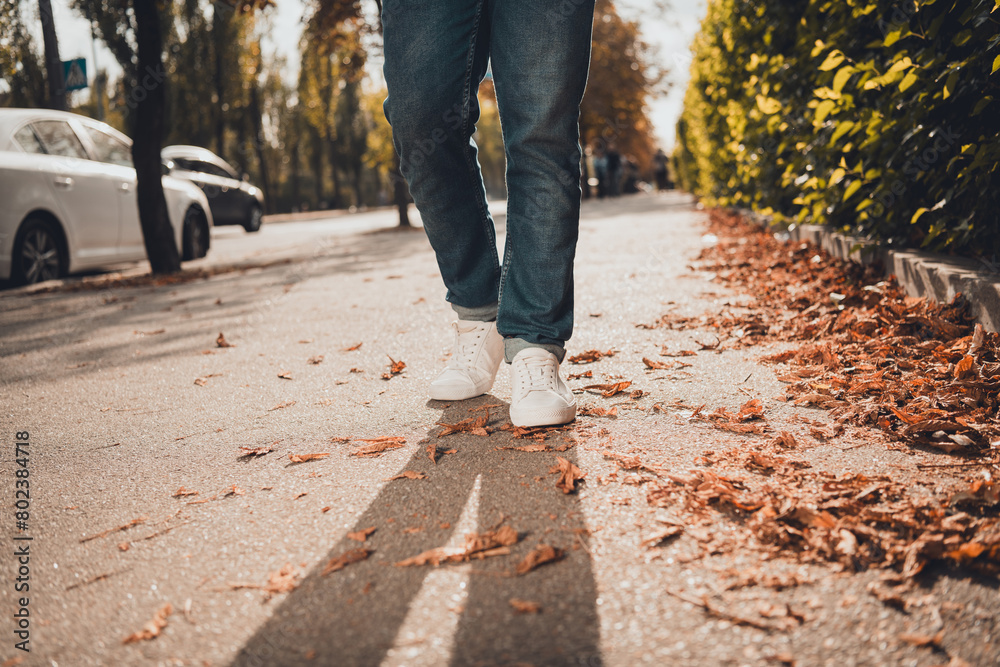 Cropped photo of man in trendy sneakers walking on road pavement sidewalk urban city street style Cropped photo of man in trendy sneakers walking on road pavement sidewalk urban city street style