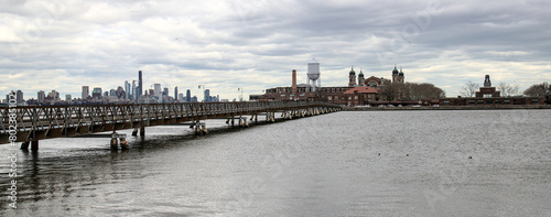 ellis island view with bridge and hudson river (from liberty state park in jersey city nj) new immigrant arrival museum historical site dark dramatic sky cloudy (york history immigration europe) photo