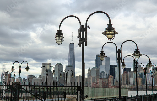 view of downtown manhattan new york city skyline with lanterns on pier (dock at libery state park jersey) nyc skyscrapers high rise commercial travel destination (dark cloudy sky) scenic waterfront photo