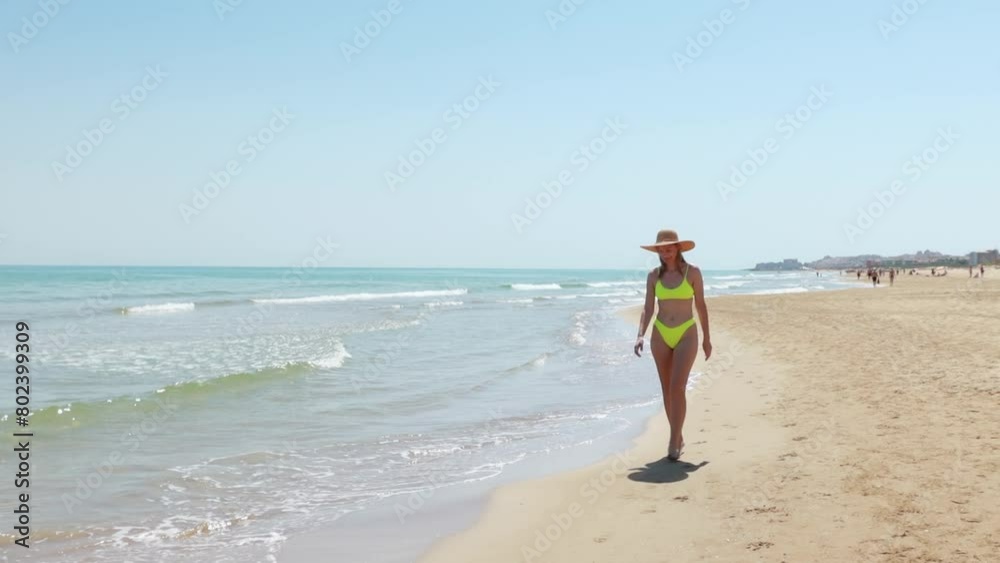 Happy young girl in hat and swimsuit walks along beach. holiday at sea. Beautiful sun light on coast. Happy young girl in hat and swimsuit walks along beach. holiday at sea. Beautiful sun light on coast.