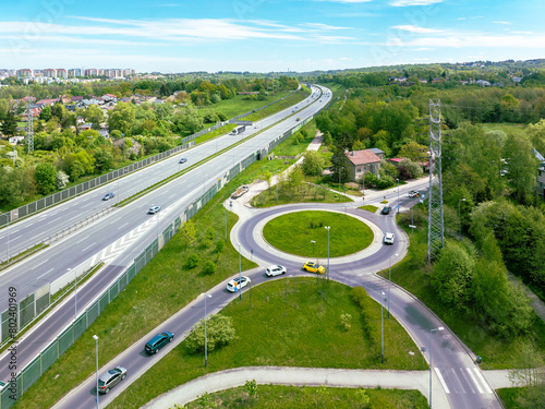 Three lane motorway A4 in Krakow, Poland. Entrance ramp and exit ramp with a traffic circle, cars and noise barriers. Aerial view