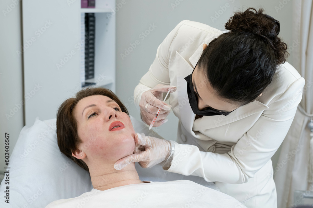 Fototapeta premium Lipolytic injection to reduce double chin, precision in care. Highlights the trend towards non-invasive contouring.