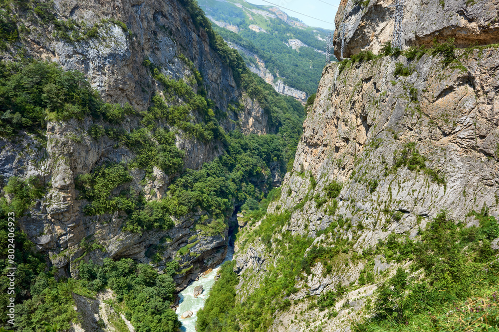 A mountain river flows in a deep gorge. View of the Cherek Gorge on a sunny summer day. Mountain kingdom