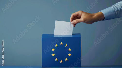 A person entering a vote into a ballot box European Union flag in background. European elections