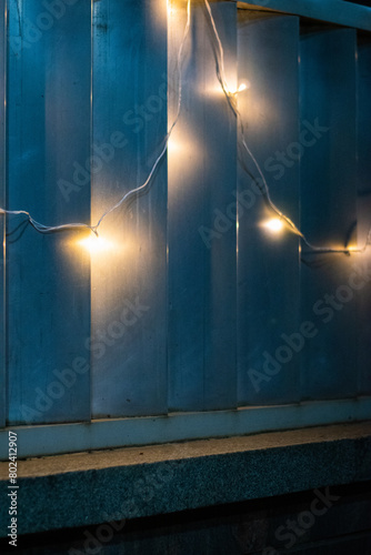Decorative garland hanging on the fence in the evening. Christmas lights.