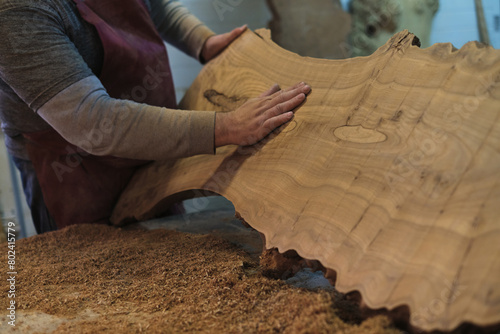 A craftsman admires the natural beauty of a large wood slab. The rich textures tell a story of the wood's life journey.