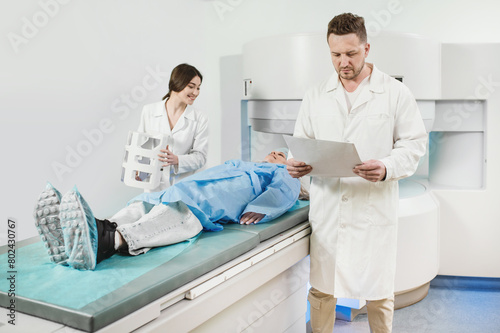 two doctors and a patient in the MRI room. Male doctor and female assistant preparing adult female patient for MRI scan	