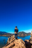 Man standing in front of a cliff with a lake and mountains in the background, clear blue sky in Valle de Bravo state of Mexico