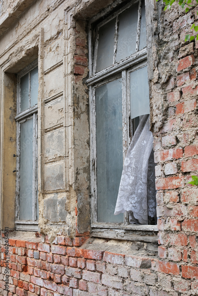 verlassenes Haus, kaputtes Fenster mit Gardine