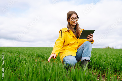 Woman Farmer on a green wheat field with a tablet. Smart farm. The concept of the agricultural business © maxbelchenko
