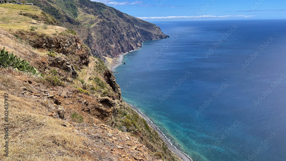 Fototapeta premium A breathtaking coastal cliff view overlooking the deep blue ocean, with rugged terrain and clear skies.