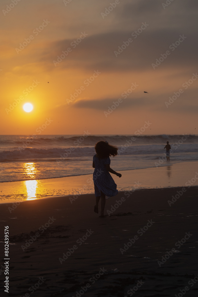 Fototapeta premium Young girl dancing in the sand silhouette during sunset in Lima Peru