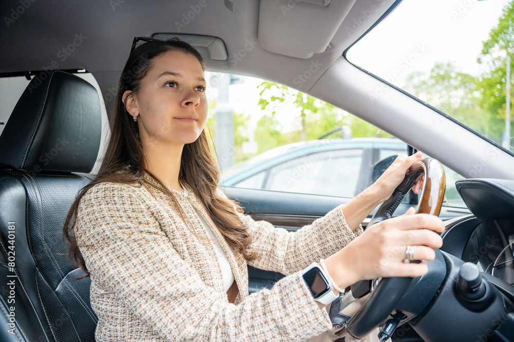 Side portrait of young caucasian woman driving car in the city