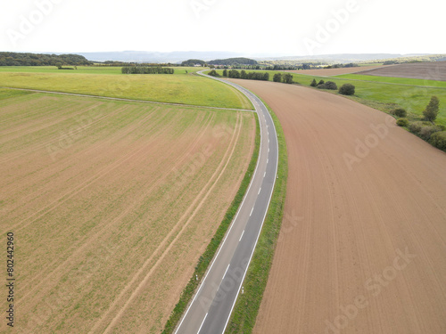Aerial view of a asphalt road with farm fields in the countryside