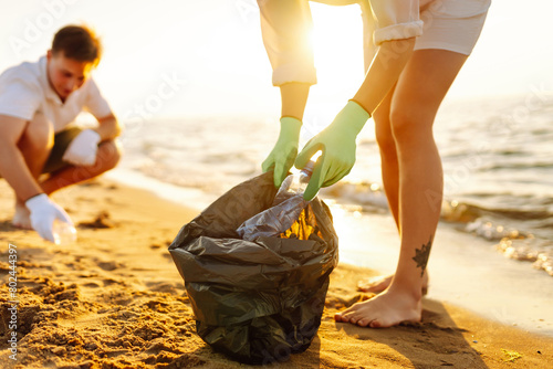 Trash on the beach. Scavengery. A volunteers collects plastic bottles on the ocean shore. The concept of environmental conservation. photo