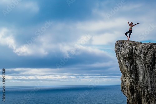 Person standing victoriously on a rock above the sea under a cloudy sky