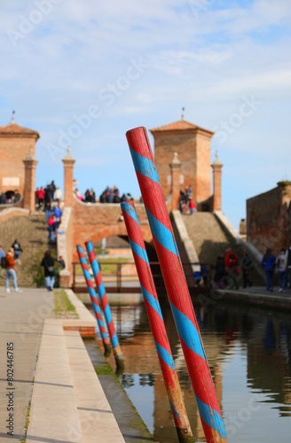mooring poles for boats in the navigable canal and the ancient bridge of COMACCHIO in Italy photo