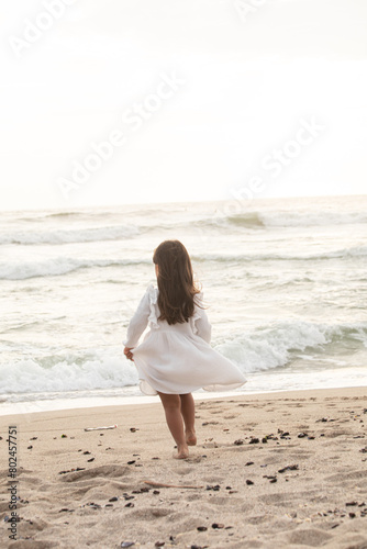 Little girl with white dress running in the beach during sunset in Lima Peru 