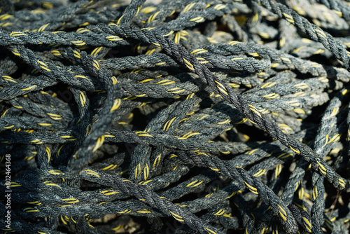 Pile of old black and yellow frayed boat rope background, pattern of twisted ropes, sailing equipment, nautical background. Close up. © surasak