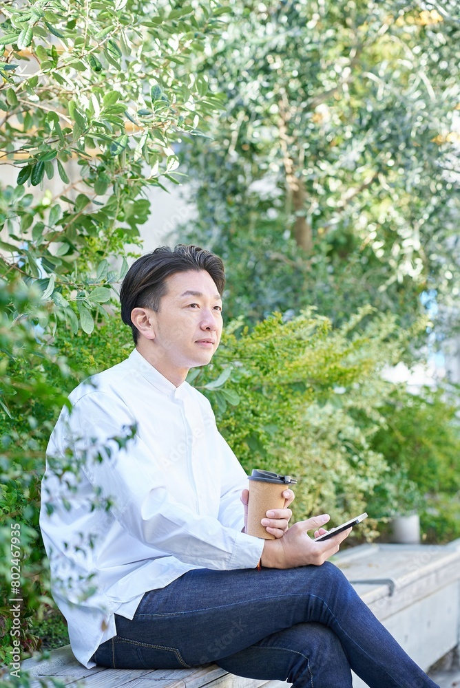 コーヒーを飲みながらスマートフォンを操作する男性 コーヒーを飲みながらスマートフォンを操作する男性