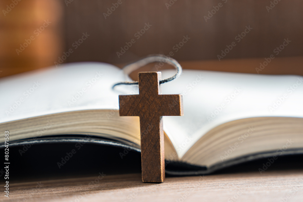 Wooden cross necklace next to open bible, Christian concept, religious symbol