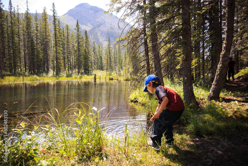 Young boy exploring a pond in a forest in summer