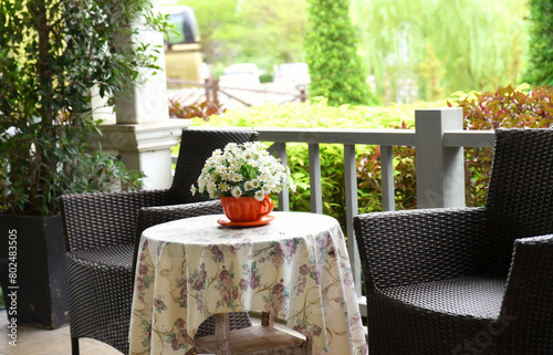 Obraz na plátně A vintage style balcony decorated with dark rattan chairs and a floral table cover