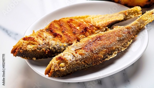 macro shot of fried fish on a plate on a white marble serving table