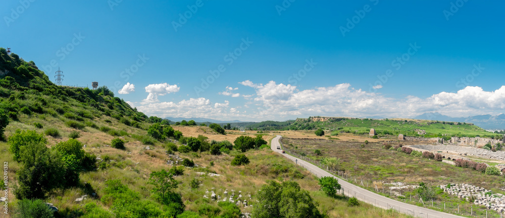 View from a height of the ancient city of Perge. Ancient city surrounded by dense green vegetation.