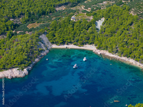 AERIAL  Scenic shot of a rugged shore of Hvar island with a few anchored boats
