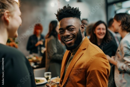 Cheerful african american man in orange jacket smiling and looking at his female colleague in cafe