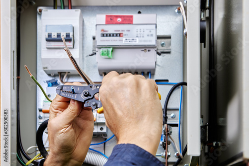 Connecting four-core, three-phase power cable to power supply in an outdoor electrical box, stripping ends of wires of insulation.