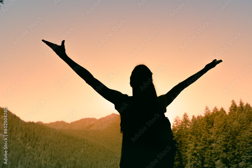 Adventurous female hiker facing the sunrise feeing free and happy in nature 