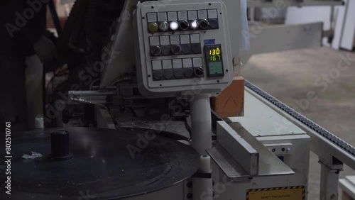 Automatic edge bander on furniture production. Worker adjusts the woodworking machine in the background. photo