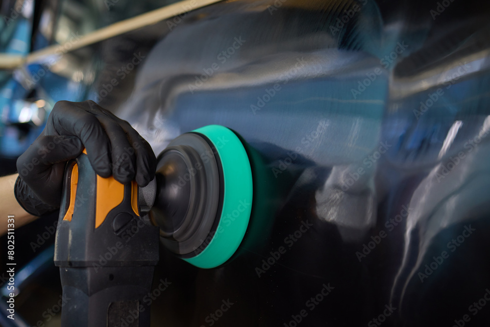 Person using machine to polish black cars automotive exterior Person using machine to polish black cars automotive exterior
