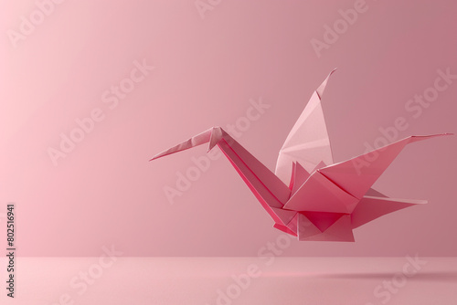 A pink origami crane suspended in mid-air against a pink backdrop.