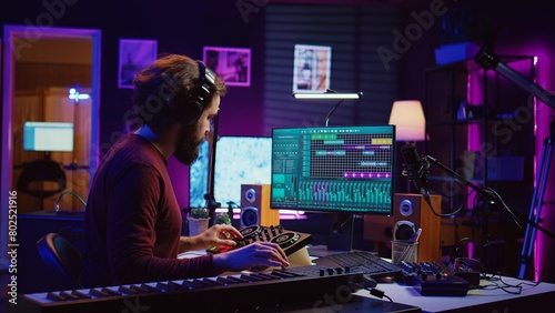 Music producer playing electronic piano notes and recording audio to adjust sound levels and create a soundtrack. Creative artist does mixing and mastering for his new songs in home studio. Camera B.