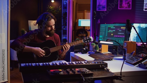 Vászonkép Music producer tuning his acoustic guitar before playing instrument, recording and mixing tunes to create new soundtracks