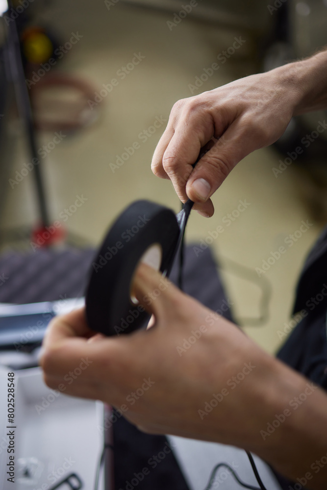 Person holds black tape on finger for automotive tire repair