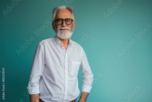 A man in a white shirt and glasses is standing in front of a blue wall