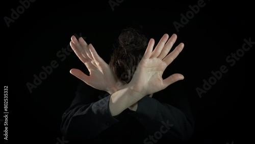Lady crossing hands no gesture indoor. An unhappy lady crossing her hands to show the stop gesture on the black background. photo