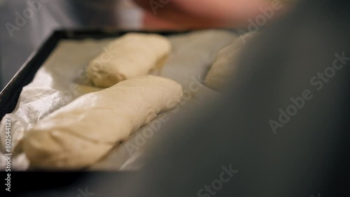 close-up in a professional kitchen a baker forms the shape of bread on baking tray slapping photo