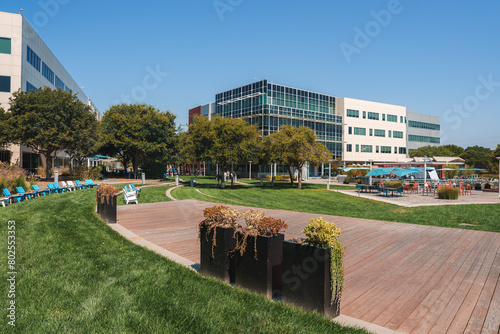 Tableau sur toile Modern corporate campus in serene suburban setting with lush lawn, pool, lounge chairs, and office building with glass facade under clear blue skies
