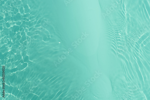 Green background with drops of water. Bluewater waves on the surface ripples blurred. Defocus blurred transparent blue colored clear calm water surface texture with splash and bubbles. Water waves.