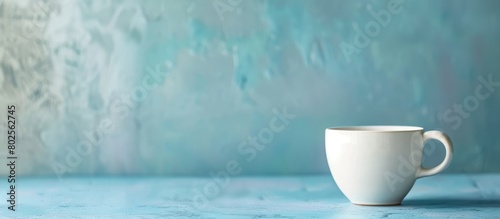 White ceramic cup on a blue table with a blurred background and space for copying. photo
