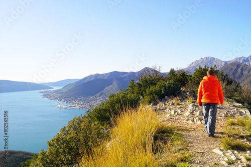 A tourist photographed from the back walking in the mountains against the backdrop of a picturesque view of the sea coast. Man on top of Sveti Vid in the vicinity of Tivat, Montenegro.