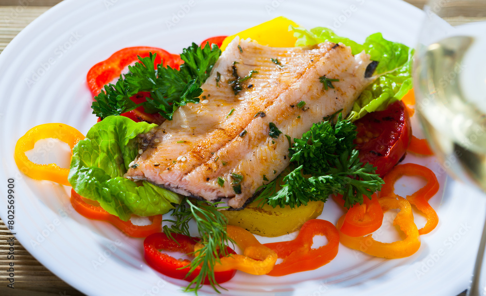 Picture of tasty fried trout fillets, served at plate with vegetables and greens..