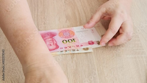 Close-up of female hands holding banknotes, inspecting authenticity paper Chinese yuan, examining bill details through magnifying glass, finance, security and counterfeit detection photo