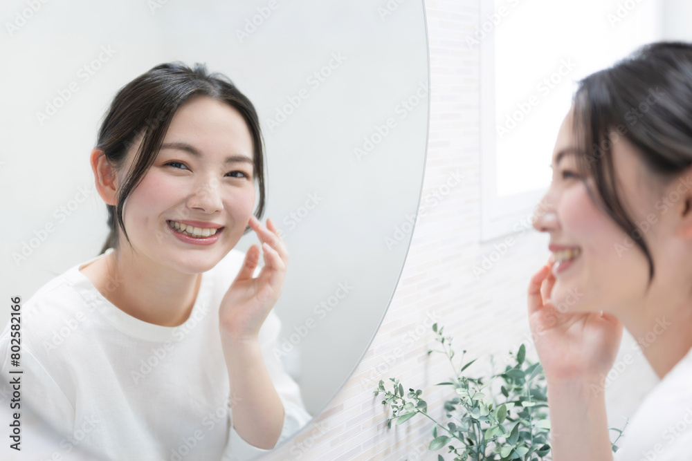 鏡を見ながら肌の質感を気にする女性 スキンケアや美容のイメージ カメラ目線 鏡を見ながら肌の質感を気にする女性 スキンケアや美容のイメージ カメラ目線